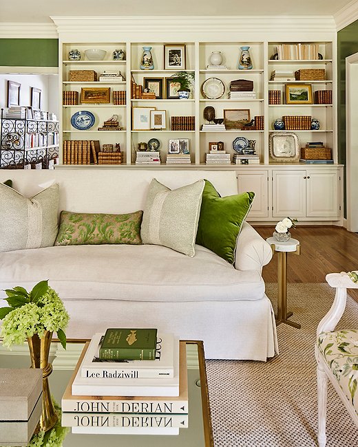 Throw pillows in solids and patterns ranging from rich emerald to barely there celadon, along with the green book and flowers on the coffee table, complement the botanical upholstery on the side chair. Photo by Laurey Glenn.

